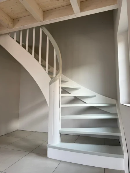 Gebogene Holztreppe mit weißer Wange und geschwungenem Holzhandlauf