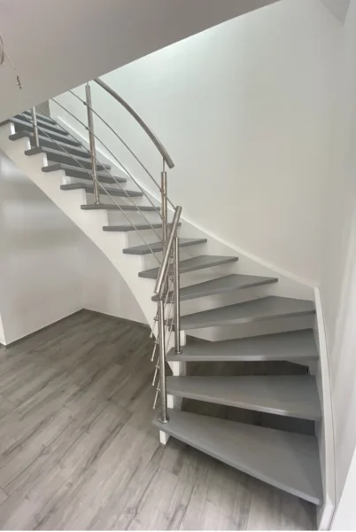 Gewendelte helle Treppe mit gebogenem Edelstahlhandlauf
