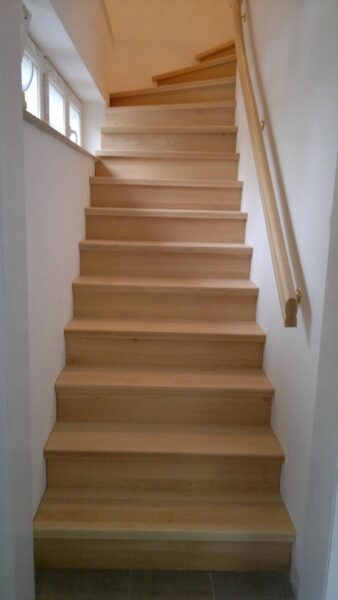 Treppe mit naturfarbenen Holzstufen und Holzhandlauf