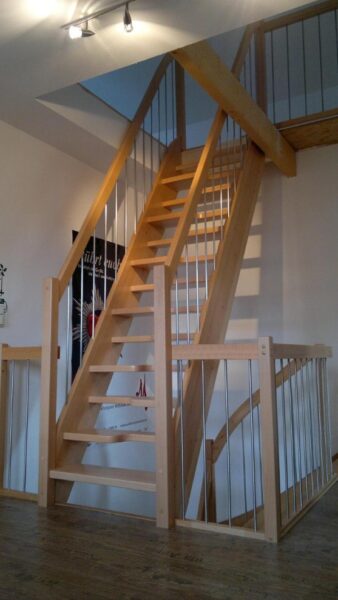 Offene Holztreppe mit schlanken Geländerstäben unter einer Dachschräge