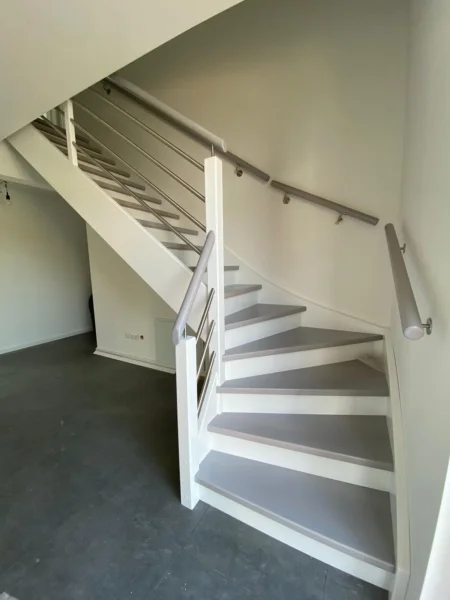 Weiße Treppe mit schlanken Geländerstäben und hellem Holzhandlauf