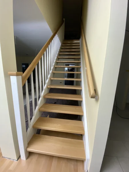 Holztreppe mit weißen Wangen und kontrastierenden Holzstufen