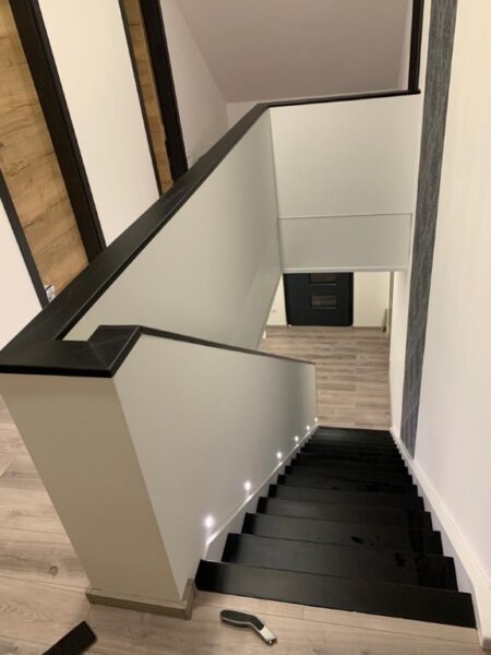 Holztreppe mit dunklen Konstruktionselementen und Handlauf