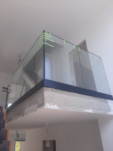 Blick von unten auf eine Glasbrüstung an der oberen Treppenöffnung