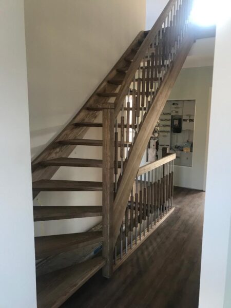 Naturfarbene Holztreppe mit Holzhandlauf und Geländerstäben
