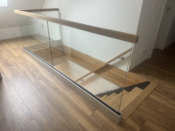 Glasbrüstung mit Holzhandlauf an einer Treppenöffnung im Obergeschoss