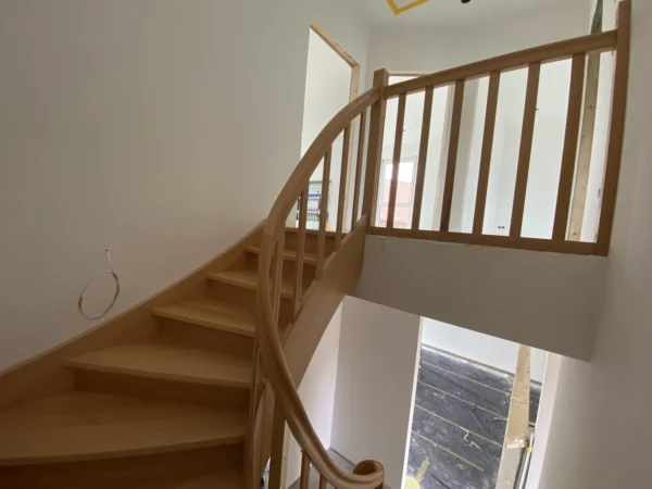 Naturfarbene Holztreppe mit gebogenen Übergängen und Holzgeländer