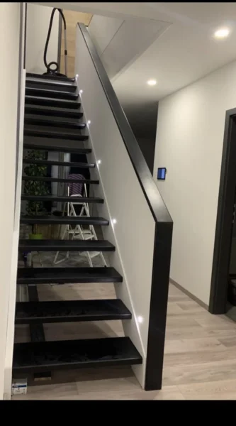 Holztreppe mit dunklen Konstruktionselementen und Handlauf