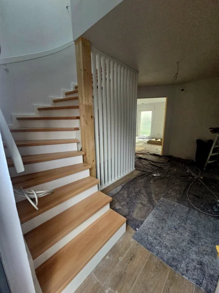 Holztreppe mit weißem Harfengeländer während der Montage