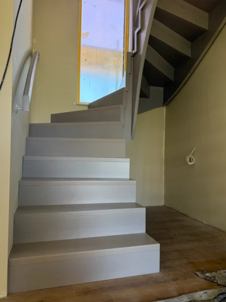 Holztreppe mit weißen Wangen und kontrastierenden Holzstufen