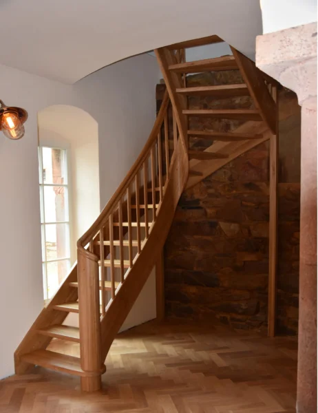 Naturfarbene Holztreppe mit gebogenen Übergängen und Holzgeländer