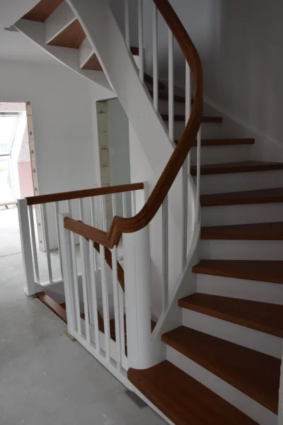 Gebogene Holztreppe mit weißer Wange und geschwungenem Holzhandlauf