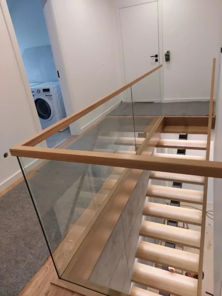 Glasbrüstung mit Holzhandlauf an einer offenen Treppenöffnung