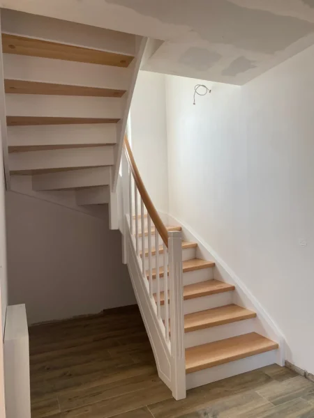 Holztreppe mit weißen Wangen und kontrastierenden Holzstufen