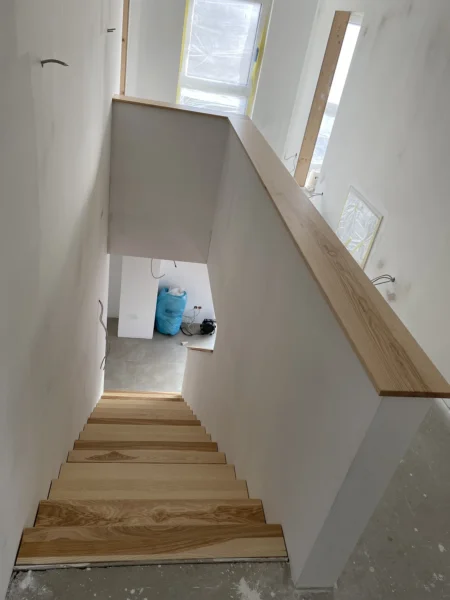 Draufsicht auf Holzstufen im Rohbau mit Holzabdeckung der Brüstung