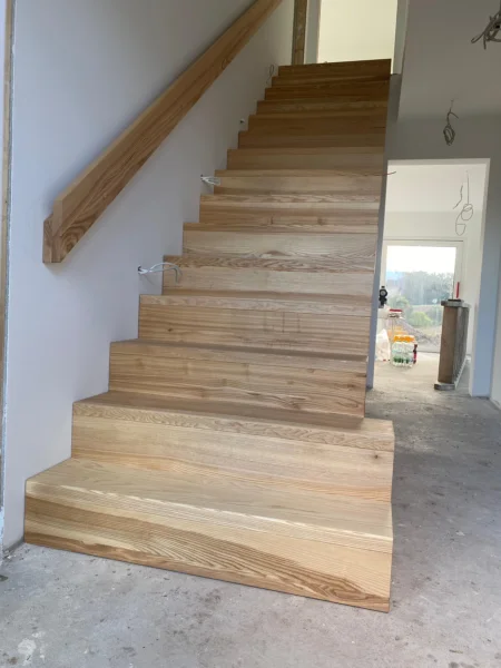Treppe mit naturfarbenen Holzstufen und Holzhandlauf
