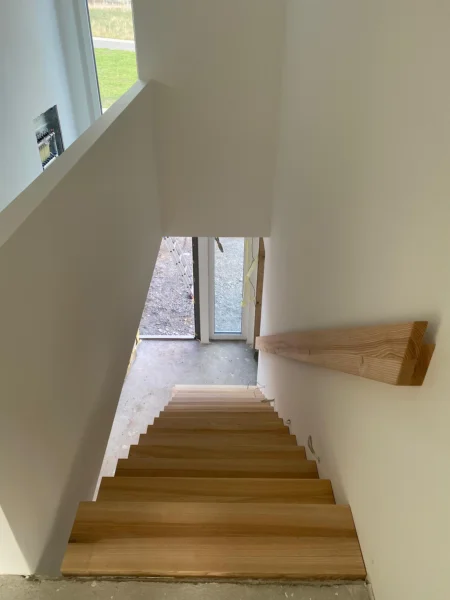 Treppe mit naturfarbenen Holzstufen und Holzhandlauf