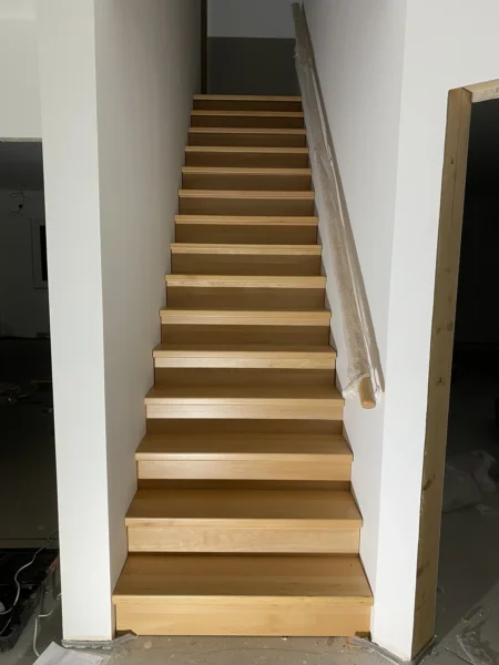 Treppe mit naturfarbenen Holzstufen und Holzhandlauf