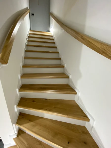 Treppe mit naturfarbenen Holzstufen und Holzhandlauf