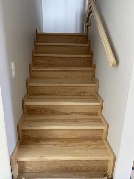 Treppe mit naturfarbenen Holzstufen und Holzhandlauf
