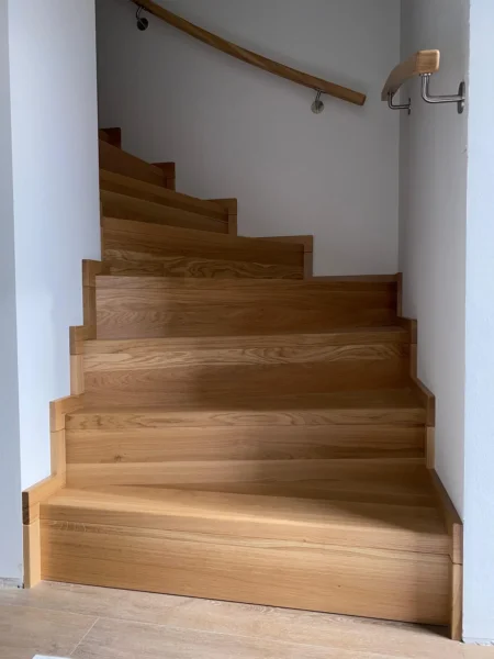 Treppe mit naturfarbenen Holzstufen und Holzhandlauf