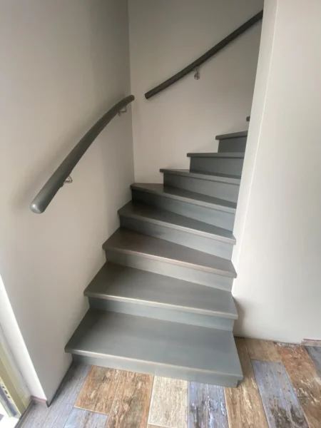 Graue geschlossene Treppe mit passendem Wandhandlauf