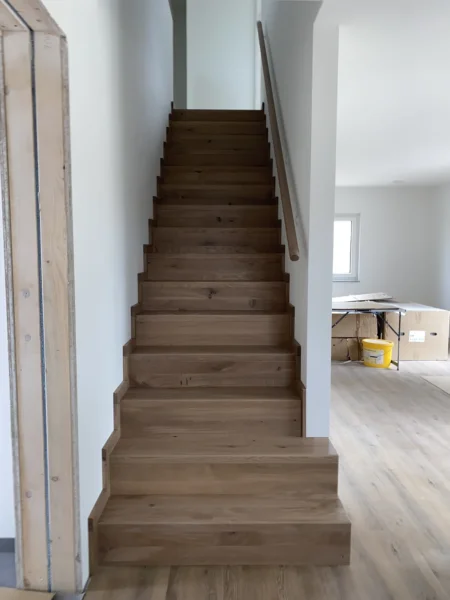 Treppe mit naturfarbenen Holzstufen und Holzhandlauf