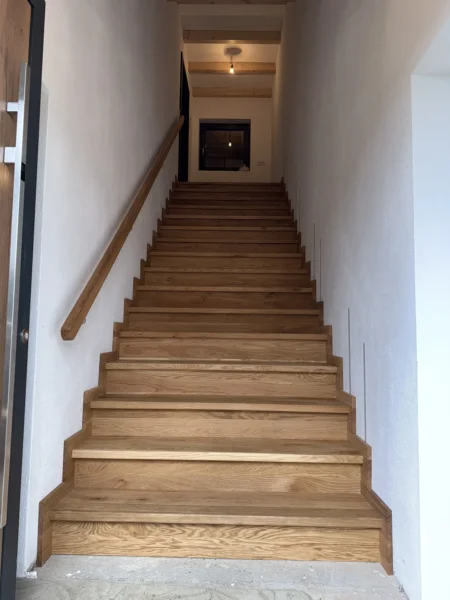 Treppe mit naturfarbenen Holzstufen und Holzhandlauf