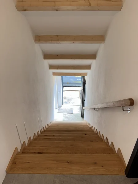 Blick entlang eines Treppenlaufs mit Holzstufen und hellem Wandhandlauf