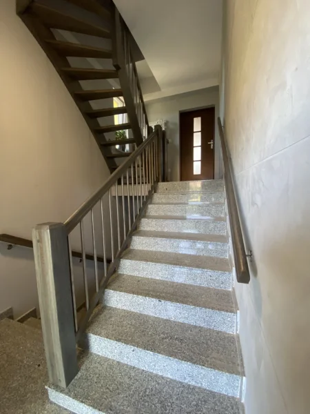 Treppe mit grauem Stufenbelag und naturfarbenem Holzgeländer