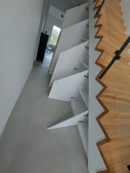 Geöffnete Stauraumtüren unter einer Faltwerktreppe aus Holz