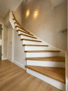 Geschlossene gewendelte Holztreppe mit weißen Setzstufen und Holzhandlauf