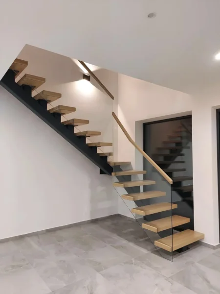 Offene Holztreppe mit einem dunklen Mittelholm und Glasgeländer