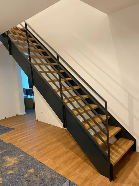 Offene Holztreppe mit dunklen Metallwangen und Metallgeländer